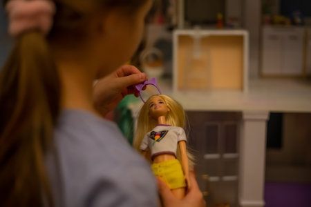 A girl plays with a doll. Funny lovely child is having fun in the childrens room.のeditorial素材