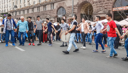 Kiev, Ukraine, September 9, 2018: Eastern men are dancing, moving in a circle, holding hands, on the square. A bearded man with a drum stands in the center of the circle. Nationality conceptのeditorial素材