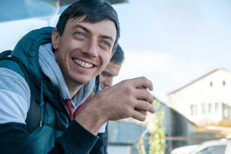Happy smiling man drinks coffee or tea from a paper cup outdoorsの写真素材