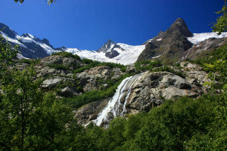 Waterfalls and glaciers and green valleys. Exotic picture - ice, water, forest, summer in one paletteの写真素材