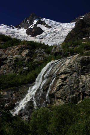 Waterfalls and glaciers and green valleys. Exotic picture - ice, water, forest, summer in one paletteの写真素材