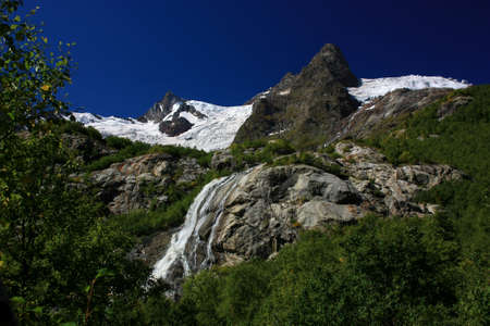 Waterfalls and glaciers and green valleys. Exotic picture - ice, water, forest, summer in one paletteの写真素材
