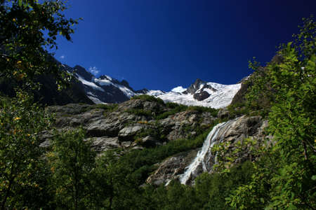 Waterfalls and glaciers and green valleys. Exotic picture - ice, water, forest, summer in one paletteの写真素材
