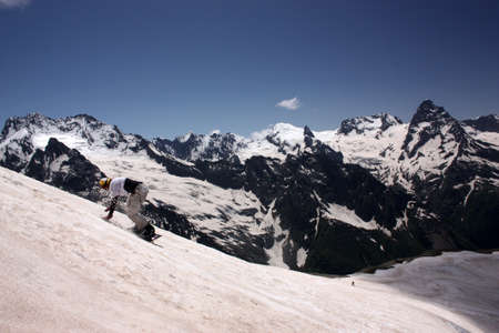 Snowboarder in the mountains, summer skiing on the boardの写真素材