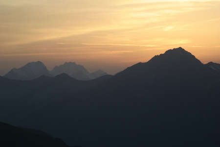 Cloudy red sunset in the mountainsの写真素材