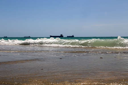 Pier on the sea with the waves and the ships on the horizon の写真素材