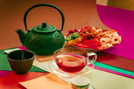 Breakfast with vitamins, dried fruits and a cast-iron green teapot on a colored background.の写真素材