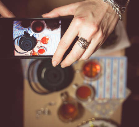 Woman hand shooting by smartphone food, breakfast tea cups. Lifestyle technology concept trendy colorsの写真素材
