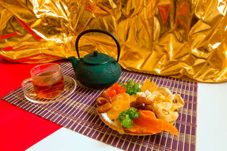 Breakfast with vitamins, dried fruits and a cast-iron green teapot on a colored background.の写真素材