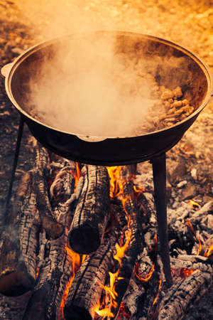 Large pot over a campfire cooking in cast-iron cauldron in nature.の写真素材