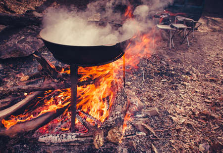 Large pot over a campfire cooking in cast-iron cauldron in nature.の写真素材