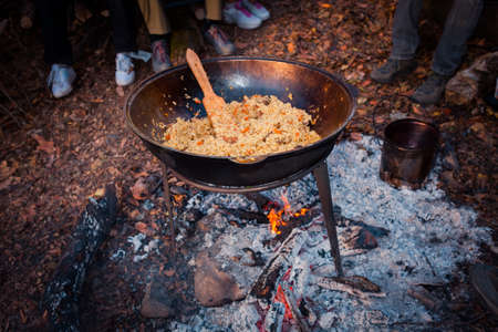 Cast iron pot and kettle outdoor, cooking on a fire. Pilaf and tea in nature.の写真素材