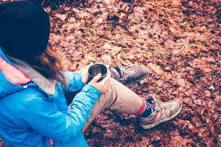 Travel girl drinking from a mug on forest and mountain lake background. Girl on vacation enjoying...
