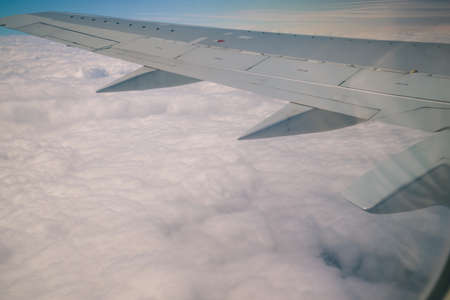 Clouds and sky with wing through window of an aircraft.の写真素材