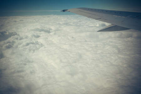 Clouds and sky with wing through window of an aircraft.の写真素材