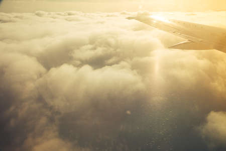 Clouds and sky with wing through window of an aircraft.の写真素材