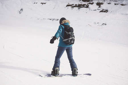 Woman snowboarder on the slopes of the resort on a winter day. Young girl on snoborde in the snow. Lifestyle vacation outdoors. The concept of vacation adventures.の写真素材