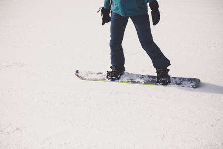 Woman snowboarder on the slopes of the resort on a winter day. Young girl on snoborde in the snow. Lifestyle vacation outdoors. The concept of vacation adventures.の写真素材