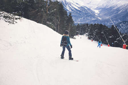 Woman snowboarder on the slopes of the resort on a winter day. Young girl on snoborde in the snow. Lifestyle vacation outdoors. The concept of vacation adventures.の写真素材