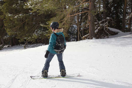 Woman snowboarder on the slopes of the resort on a winter day. Young girl on snoborde in the snow. Lifestyle vacation outdoors. The concept of vacation adventures.の写真素材