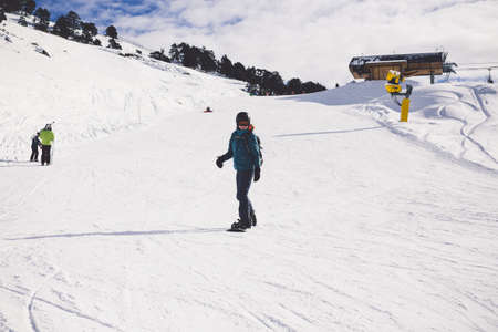 Woman snowboarder on the slopes of the resort on a winter day. Young girl on snoborde in the snow. Lifestyle vacation outdoors. The concept of vacation adventures.の写真素材