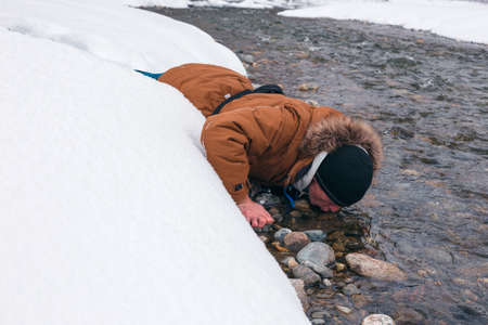 Man positive rejoices lying in the snow against the backdrop of mountain scenery.
Lifestyle adventure. The concept of travel, health and well-being.の写真素材