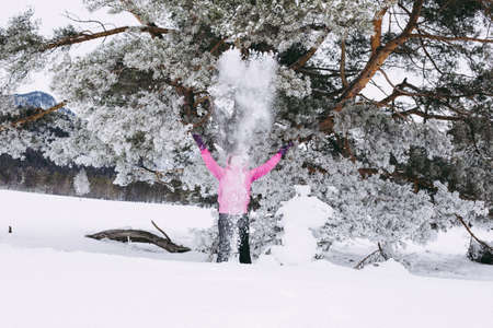 Woman with holiday Lifestyle in the winter forest. Happy little girl playing in the snow against a pine forest. The concept of active holiday adventures in the wild.の写真素材