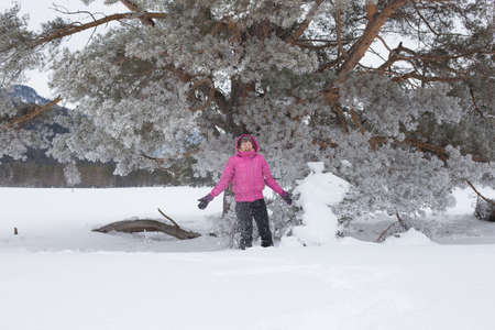 Woman with holiday Lifestyle in the winter forest. Happy little girl playing in the snow against a pine forest. The concept of active holiday adventures in the wild.の写真素材