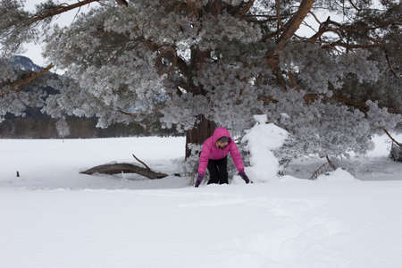 Woman with holiday Lifestyle in the winter forest. Happy little girl playing in the snow against a pine forest. The concept of active holiday adventures in the wild.の写真素材
