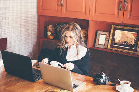 View of a young prospective business woman in a restaurant. The girl is working on the computer at lunch sitting indoor in urban cafe. The concept of city lifestyle of successful people.の写真素材