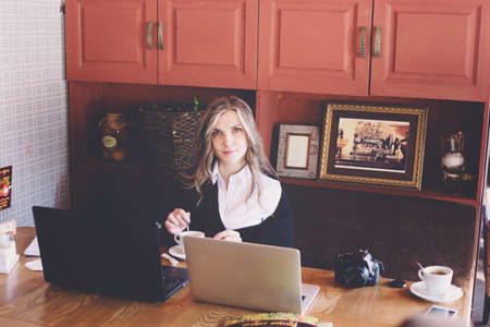 View of a young prospective business woman in a restaurant. The girl is working on the computer at lunch sitting indoor in urban cafe. The concept of city lifestyle of successful people.の写真素材