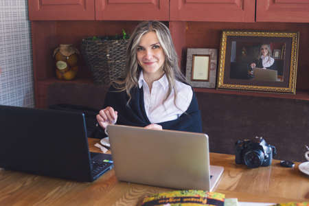 View of a young prospective business woman in a restaurant. The girl is working on the computer at lunch sitting indoor in urban cafe. The concept of city lifestyle of successful people.の写真素材