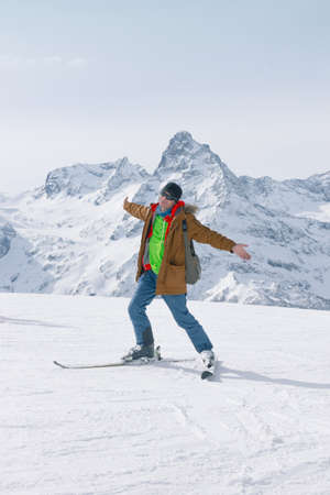 Alpine skiing in the high mountains. Active positive skier rejoices against the background of snowy peaks. The concept of skiing. Lifestyle is active in winter sports.の写真素材