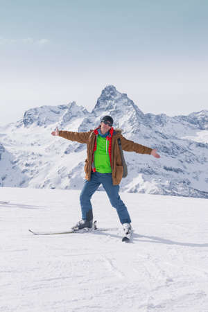 Alpine skiing in the high mountains. Active positive skier rejoices against the background of snowy peaks. The concept of skiing. Lifestyle is active in winter sports.の写真素材