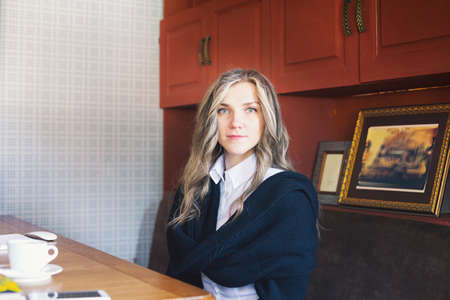 View of a young prospective business woman in a restaurant. The girl is working on the computer at lunch sitting indoor in urban cafe. The concept of city lifestyle of successful people.の写真素材