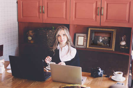 View of a young prospective business woman in a restaurant. The girl is working on the computer at lunch sitting indoor in urban cafe. The concept of city lifestyle of successful people.の写真素材