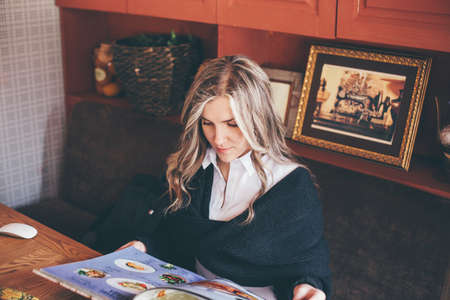 View of a young prospective business woman in a restaurant. The girl is working on the computer at lunch sitting indoor in urban cafe. The concept of city lifestyle of successful people.の写真素材