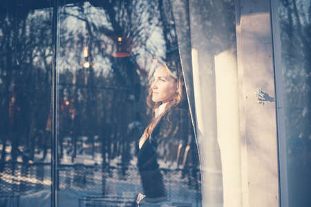 The woman looked out the window of the cafe. A young girl looks through a meeting through the window.の写真素材