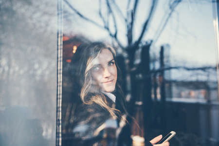 The woman looked out the window of the cafe. A young girl looks through a meeting through the window.の写真素材
