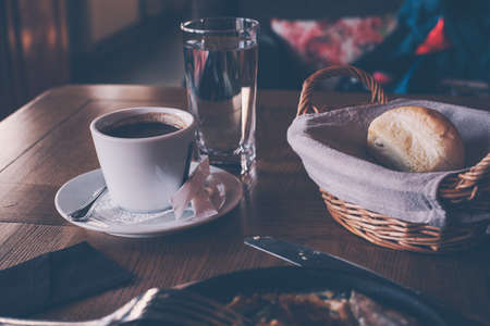 A cup of coffee and breakfast in a cozy retro style cafe. Modern scene of the restaurant table for breakfast.の写真素材