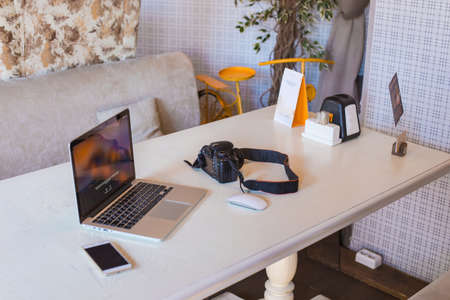 Laptop, phone, camera on a modern desktop. A view on the background of a laptop desk and digital devices in a cafe.の写真素材