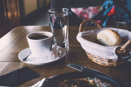 A cup of coffee and breakfast in a cozy retro style cafe. Modern scene of the restaurant table for breakfast.の写真素材