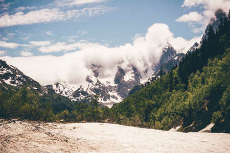 High mountains in the snow, green valleys and river beds. Lifestyle Active leisure, hiking, tourism. Picturesque landscapes and snow peaks in the summer season.の写真素材