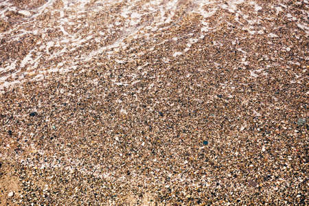 Sea pebble beach stones. Background texture coastline surf with wet round cobblestones.の写真素材