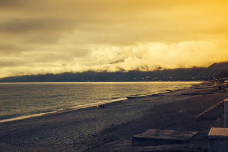 Sunset over the ocean. Prolonged exposure to sunrise and waves washing away the beach.The beach in the evening in a dramatic scene. Abkhazia, the Black Sea.の写真素材