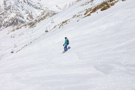 Girl snowboarder on the background of mountains in the winter season. Recreation in the ski resort. The concept of snowboarding, success, lifestyle, sport, recreation, adventure, travel.の写真素材