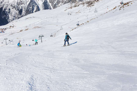 Girl snowboarder on the background of mountains in the winter season. Recreation in the ski resort. The concept of snowboarding, success, lifestyle, sport, recreation, adventure, travel.の写真素材