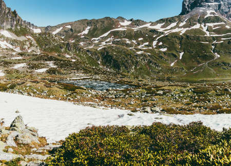 Mountain landscape in summer, quiet idyllic scene of green glades, peaks and snowy slopes. Lifestyle tourism and travel, adventure. Alpine rocky view of the meadow and the lake.の写真素材