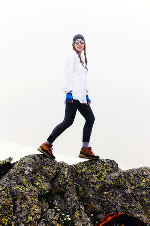 Young traveler woman a walk against the background of an epic rock scene and fog, enjoying an amazing walk, walking and explore nature. Tourist girl hipster Lifestyle Summer journey vacations outdoor.の写真素材