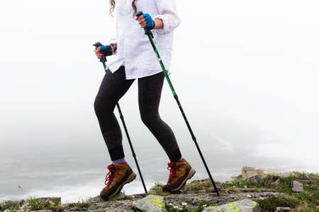 The girl's legs against the background of the landscape in foggy weather during a walk. Wild nature in the clouds. The concept of a way of life, adventures, pleasures and relaxing hikes.の写真素材